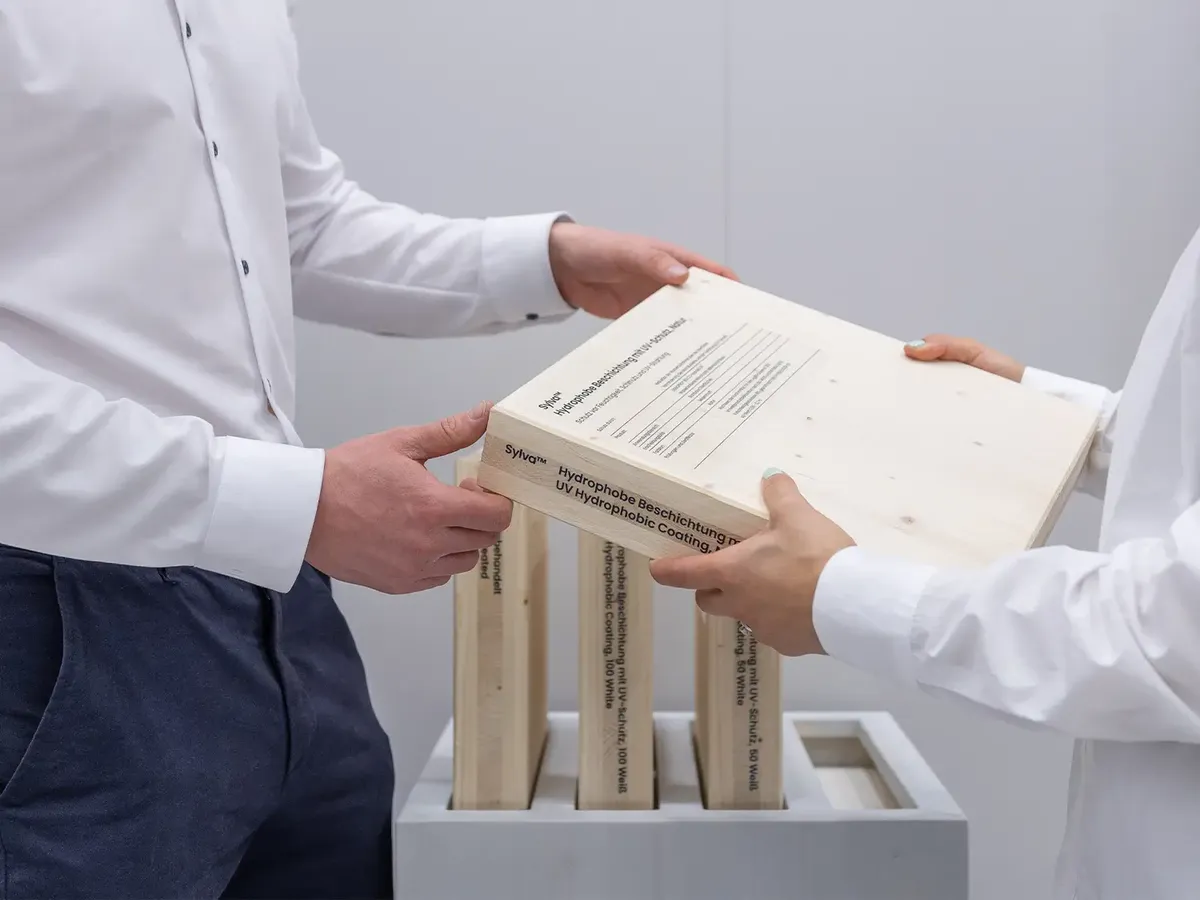Close-up of a product handover at the Stora Enso stand: technical documentation on the hydrophobic coating Sylva