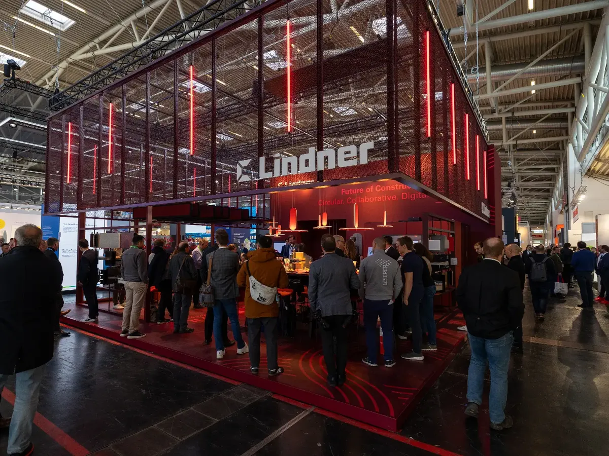 Lindner Group stand at BAU 2025: striking red LED lighting and expanded metal architecture with the »Future of Construction« claim, a busy consultation area