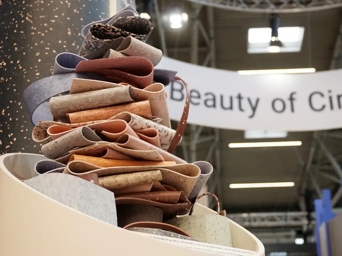 Artfully arranged vinyl flooring offcuts in earth tones, stacked in front of a »Beauty of Cir« banner on the Tarkett stand at BAU 2025