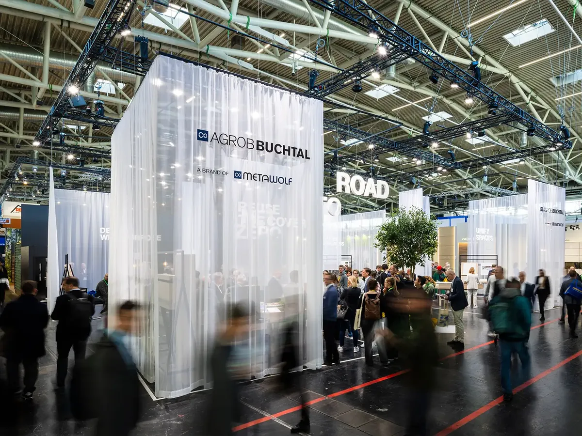 Agrob Buchtal stand with transparent curtains and the »Road to Net Zero« concept, a busy trade fair atmosphere with visitors moving in the foreground